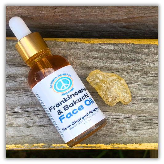 Bottle of Frankincense and Bakuchi face oil with dropper next to a piece of frankincense resin on wooden surface